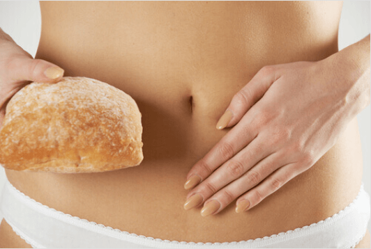Ευαισθησία στη γλουτένη - Γυναίκα κρατά το στομάχι της και ψωμί