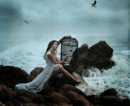συναισθηματικό σφουγγάρι Γυναίκα με κλουβί πλάι στον ωκεανό