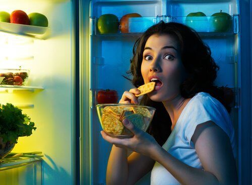 αποφύγετε την αύξηση βάρους Γυναίκα τσιμπολογάει μπροστά στο ψυγείο