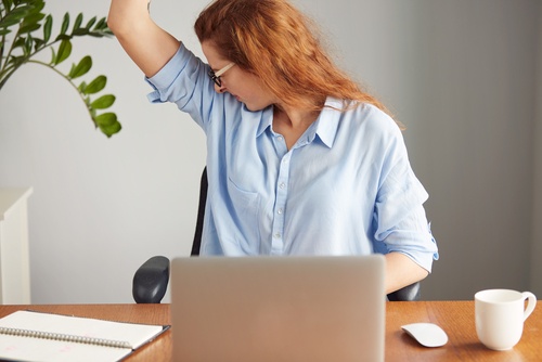 γυναίκα σε γραφειο με σηκωμένο χέρι- σημάδια που δίνουν οι μασχάλες σας 