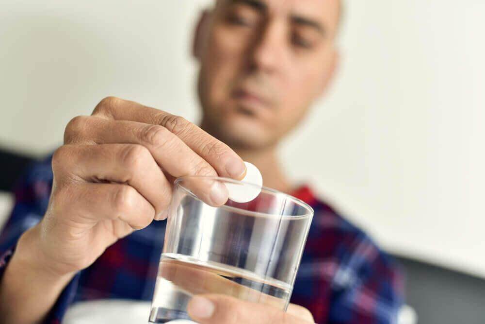  Άνδρας βάζει χάπι σε ποτήρι με νερό