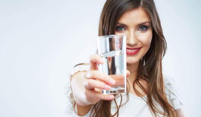 Παρασκευάστε ένα καθαρτικό χυμό - Γυναίκα κρατά ένα ποτήρι νερό