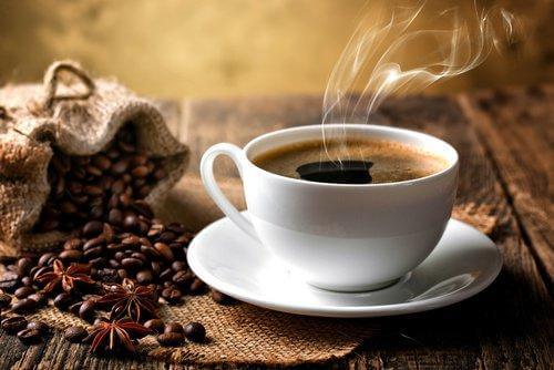 ζεστός καφές σε φλιτζάνι και κόκκοι καφέ