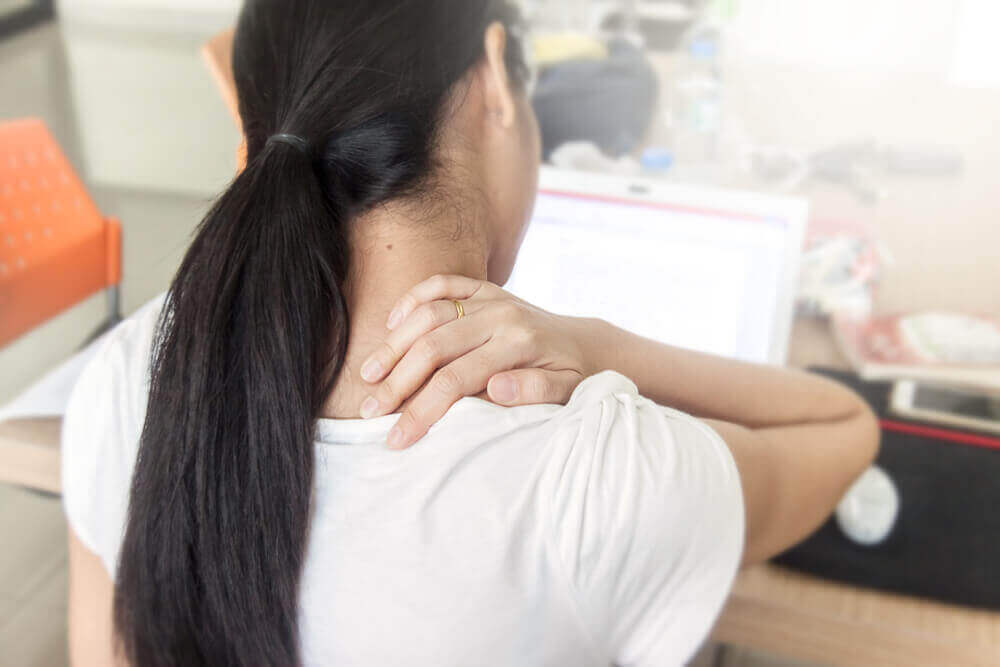 Πιθανές αιτίες για τον πόνο στην πλάτη - Γυναίκα πιάνει τον αυχένα της