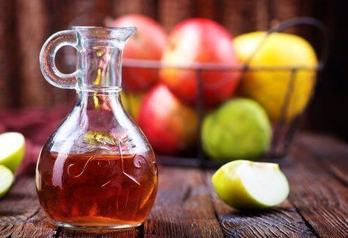 μηλόξυδο σε γυάλινο μπουκάλι και μήλα σε μπολ