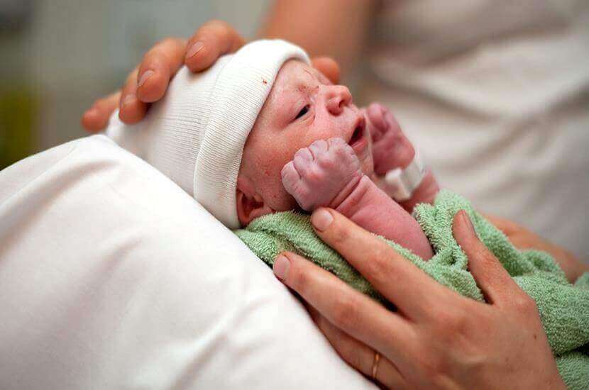 νεογέννητο τυλιγμένο με πετσέτα στην αγκαλιά
