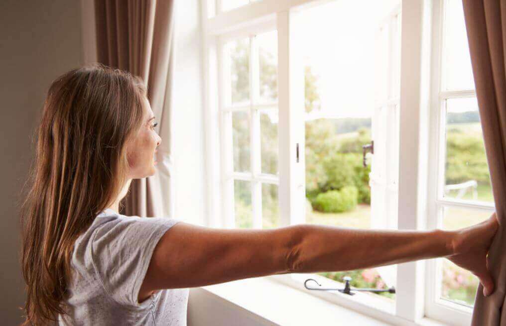 γυναίκα που ανοίγει το παράθυρο, υγρασία στο σπίτι
