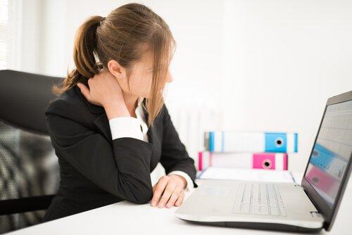 Αντιμετωπίστε τον μυοσπασμό στον αυχένα - Γυναίκα κάθεται μπροστά από υπολογιστή