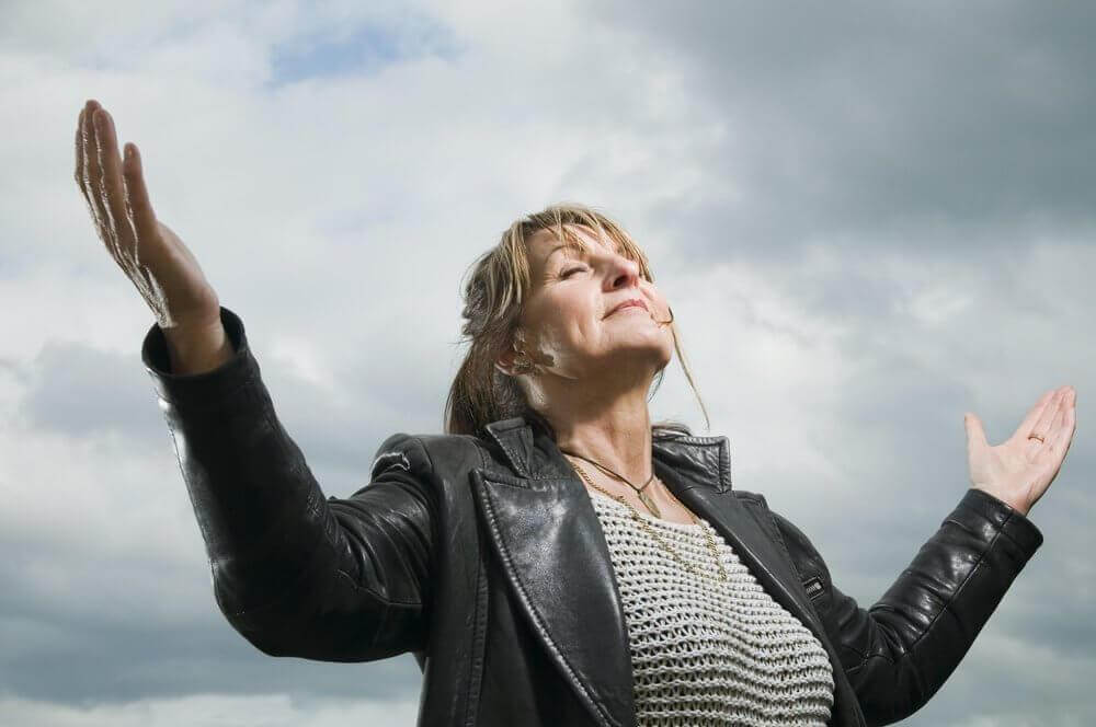 Κρίση της μέσης ηλικίας - Γυναίκα κοιτά ψηλά με ανοιχτά χέρια