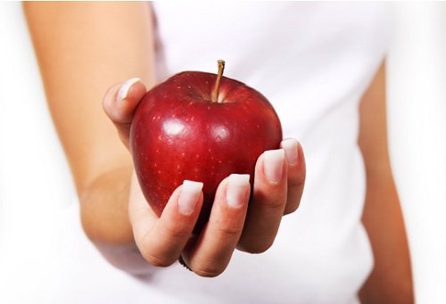 Συνταγές με ανανά - Γυναίκα που κρατάει κόκκινο μήλο