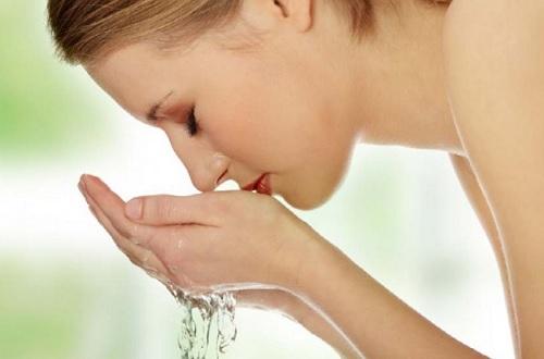 Γυναίκα πλένει με νερό το πρόσωπό της