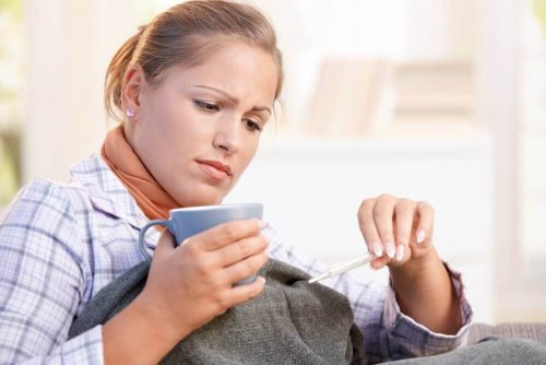 Γυναίκα με πυρετό κοιτά το θερμόμετρο