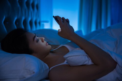 Γυναίκα ξαπλωμένη κοιτά το κινητό της