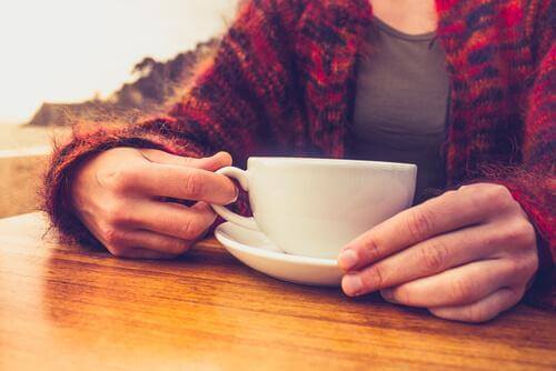 Γυναίκα κρατά κούπα με καφέ