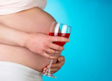 Έγκυος γυναίκα κρατά ποτήρι με κρασί
