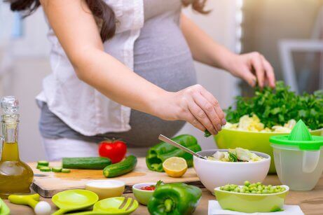 Έγκυος γυναίκα μαγειρεύει λαχανικά