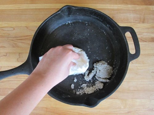 Άτομο καθαρίζει τηγάνι με αλάτι