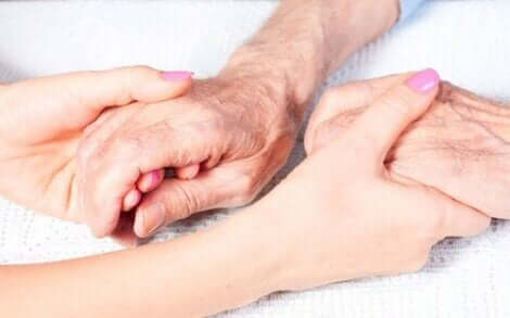 Νεαρή γυναίκα κρατά τα χέρια ηλικιωμένου ατόμου