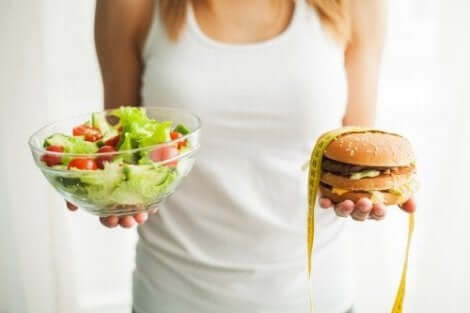 Γυναίκα κρατά μια σαλάτα και ένα burger