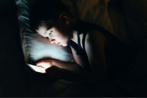 Παιδί στο κρεβάτι κρατά κινητό
