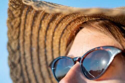 Γυναίκα φορά γυαλιά ηλίου και καπέλο