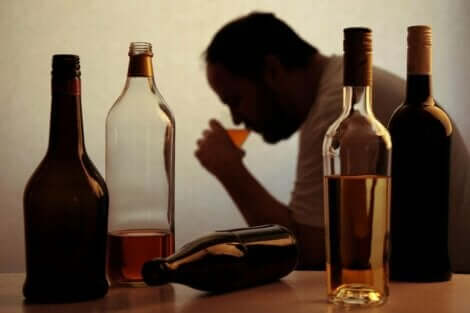 Μπουκάλια άδεια και άνδρας πίνει αλκοόλ