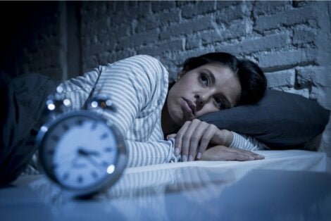 Γυναίκα κοιτάζει το ρολόι δίπλα από το κρεβάτι