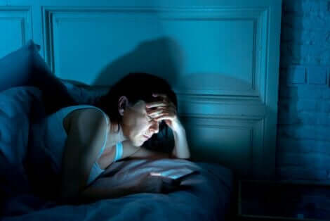 Γυναίκα ασχολείται με το κινητό στο κρεβάτι
